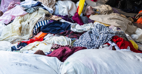 A pile of different used second hand clothes selling at a flea market in Thailand