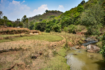 small river flowing near by  greenery mountain with blue sky background.