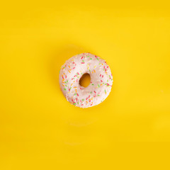 Fototapeta na wymiar Square poster with glazed donut with colorful sprinkles on yellow background. Sweet pastries for Fat Thursday.