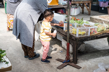 Obraz premium Thai young muslim mother bring her baby boy going to local market for buying vegetable.