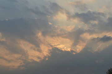 The light of the rising sun in the morning surrounded by clouds.