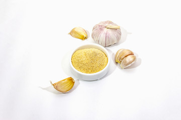 Ripe garlic isolated on white background. Fresh garlic cloves and powder in ceramic bowl. Spice cooking background