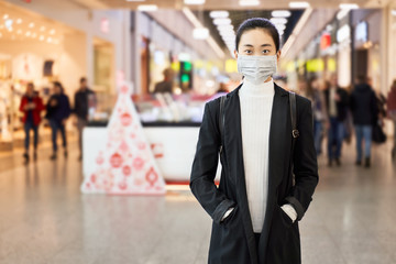Alarmed female traveler wears medical mask to protect against coronavirus, afraid of infection, in shopping center. Deadly coronavirus in China 2019 2020 2019-nov. Free space for text or advertising.