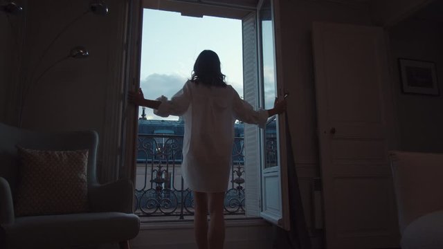 Young girl in a white shirt opening door to balcony with a view