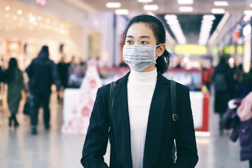 Alarmed female traveler wears medical mask to protect against coronavirus, afraid of infection, in shopping center. Deadly coronavirus in China 2019 2020 2019-nov. Free space for text or advertising.