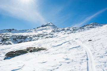 Spectacular winter mountain view with ski trail ascending a slope.