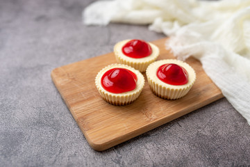 Mini cheesecakes with cherry topping, healthy summer treat on grey stone table