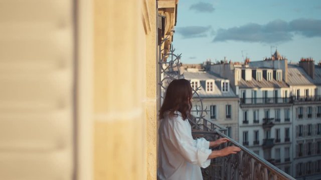 Smiling woman in a white shirt on a balcony in Paris
