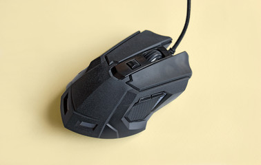 Matte modern black gaming mouse with buttons on a light yellow background.