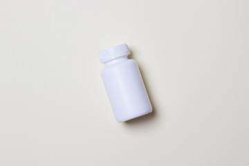 White plastic medical container for pills on yellow colored paper background