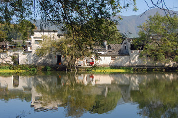 Fototapeta na wymiar Hongcun Ancient Town in Anhui Province, China. A beautiful view of the old buildings of Hongcun with their reflection in the water of Nanhu Lake and trees. The pretty, ancient town of Hongcun in China