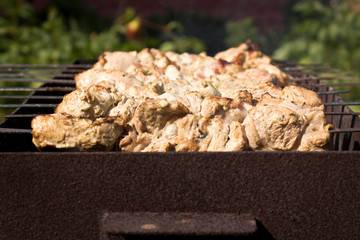 Kebab grilling on metal skewers. Meat on the grill. Close up.