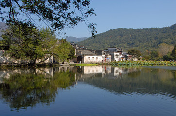 Fototapeta na wymiar Hongcun Ancient Town in Anhui Province, China. Beautiful view of the old buildings in Hongcun with their reflection in the blue water of Nanhu Lake. The pretty, ancient town of Hongcun in China.