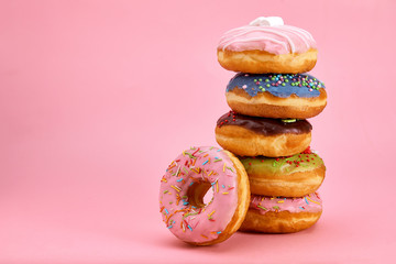 Sweet donuts stacked in a stack on a pink background. Copy space, game of color, sweet life. - Powered by Adobe