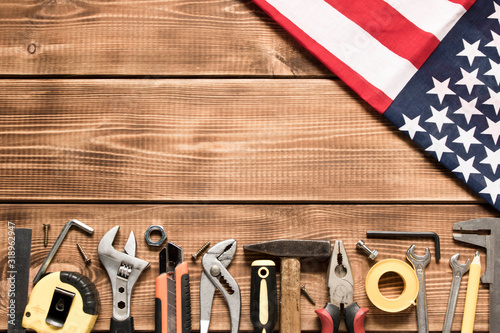 Labor day. American flag and various tools on a wooden background. The concept of labor day. Empty space for text.