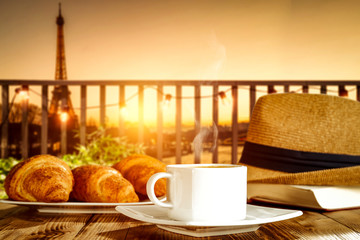 Fresh hot coffee on wooden table and blurred background of Paris city landscape. 