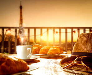 Fresh hot coffee on wooden table and blurred background of Paris city landscape. 