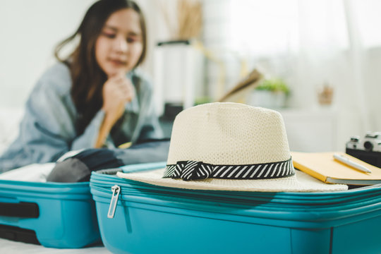 focus vintage hat on green suitcase with young asian woman traveler prepare and packing clothes into suitcase for holiday vacation at home, summer holiday, backpacker, travel and lifestyle concept