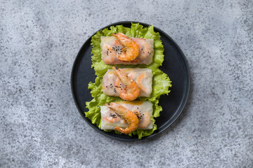 Vietnamese food spring rolls with shrimps in rice paper on grey. View from above. Asian cuisine. Horizontal orientation.