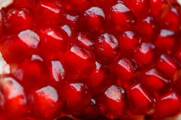 Red ripe and juicy seeds of fresh pomegranate fruit close-up.