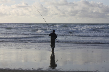 Biscarrosse. Mann geht im Ozean angeln.