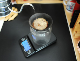 Black porous ceramic paperless coffee filter on glass jug. Gooseneck kettle. Electronic scale. Manual brewing still life