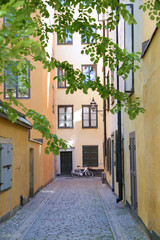 Fototapeta na wymiar Narrow cobblestone street with a bicycle and yellow medieval houses of Gamla Stan historic old center of Stockholm, Sweden