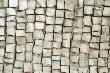 Texture of a wall made of small stones. The wall is covered with white granite cubes.