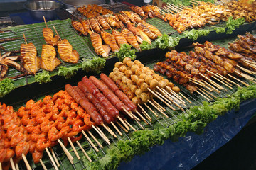 Variety of grilled Thai street food in sticks. Shrimps, squids, sausage, satay, chicken meat, tofu balls. 