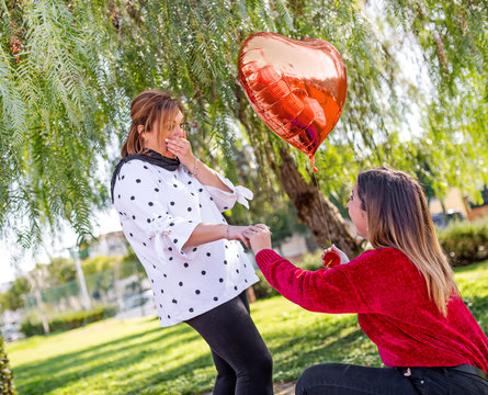 lesbian girl proposing to heart shaped balloon girl, surprised girl, lifestyle concept