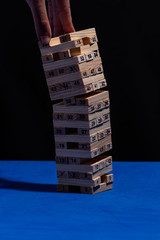 Juego de madera Torre de Babel en fondo negro y mesa azul con nmeros en cada ficha de madera y luz dura. La sicologa del hombre. Jenga jugando en equipo