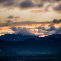 Silhouette of the Austrian Alps covered with clouds during sunset
