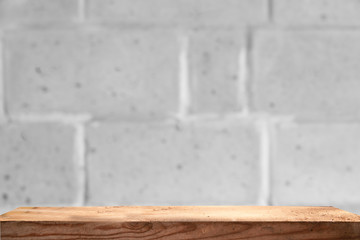 Empty wooden table on a light concrete background, blurred brick wall, empty space for the product above.