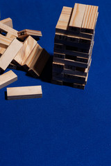 Pila de Bloques de madera sobre mesa en color azul clásico con luz dura y sombras marcadas y los...
