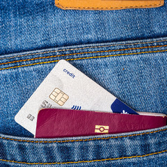 Closeup of a contactless credit card and EU passport peeking out of blue jeans back pocket