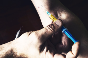 Hand making syringe injection of heroin.