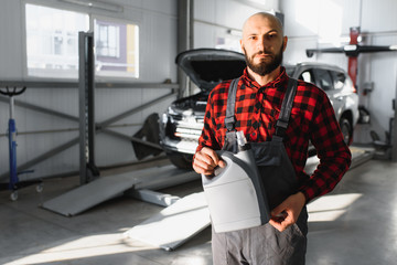 Fototapeta premium the car mechanic replaces the oil in the car. Car mechanic replacing and pouring fresh oil into engine car.