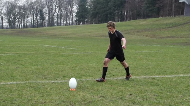 Kicking a conversion in Rugby. A player kicks the ball  off a tee during a match. Slow Motion Speed Ramping - Stock Video Clip Footage
