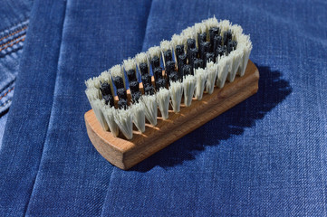 a clothes brush lies on folded jeans.