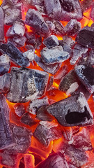 Hot red coals texture. Burning charcoal background. Close-up of hot charcoals lying in a barbeque grill. 