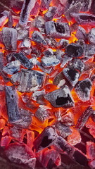 Hot red coals texture. Burning charcoal background. Close-up of hot charcoals lying in a barbeque grill. 