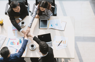 Top view of business people putting their hands together. Friends with stack of hands on the meeting table in the office, showing unity and teamwork. Business concept.
