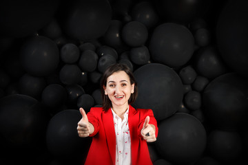 Young woman with lucky face extended arms with thumbs up. orecast is good, moving to success. Girl in red on black bubble background. Copy space