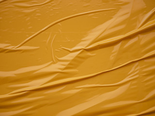 Yellow vinyl film overlapped pieces. Background from a film with a wavy texture glued to the surface