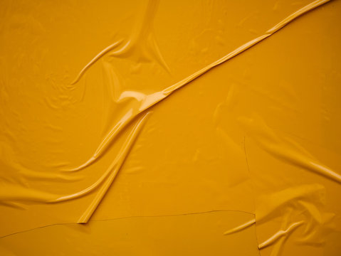 Yellow vinyl film overlapped pieces. Background from a film with a wavy texture glued to the surface