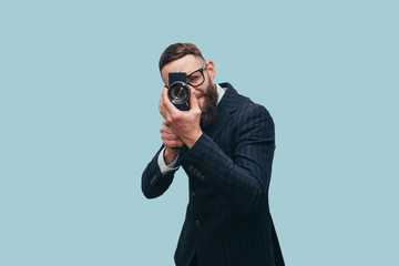 Filmmaker with a vintage lomo camera. Professional Videography. Man with beard in trendy formal suit. Studio