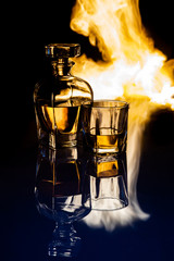 Karafka z whisky oraz szklanka na tle płomieni ognia, efekt odbicia - obrazy, fototapety, plakaty