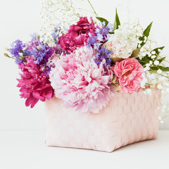 Bouquet of beautiful flowers with peonies and cornflowers in basket