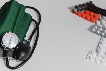 stethoscope, sphygmomanometer and pills  on white background