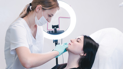 Beautician hands making botox injection in female lips. The doctor cosmetologist makes lip...
